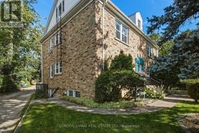 London South (South F) multi-family for rent - A brick building with a green awning is surrounded by trees and grass.