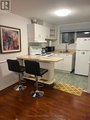 Whitby (Lynde Creek) apartment for rent - A kitchen with a white fridge, black chairs and a wooden table.