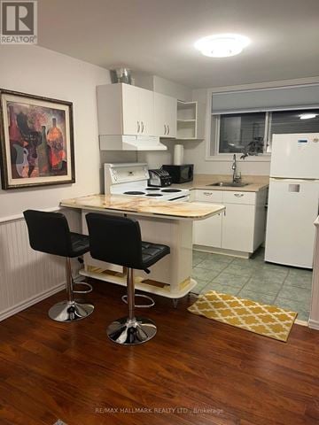 Whitby (Lynde Creek) apartment for rent - A kitchen with a white fridge, black chairs and a wooden table.