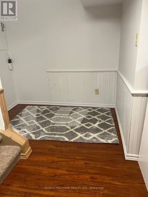 Whitby (Lynde Creek) apartment for rent - A hallway with a rug on the floor and a wooden staircase on the left.