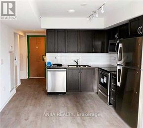 Toronto (Bendale) condo for rent - A kitchen with black cabinets and a white fridge.