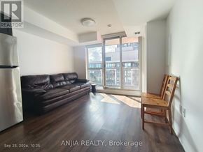 Toronto (Bendale) condo for rent - A living room with a black leather couch and wooden floors.