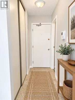 Casselman multi-family for rent - A hallway with a white door, a brown rug, and a wooden table with a plant on it.