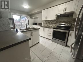 Brampton (Sandringham-Wellington) apartment for rent - A kitchen with white cabinets and a black counter top.