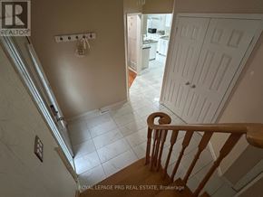 Brampton (Sandringham-Wellington) apartment for rent - A white door is in a hallway with a wooden staircase.