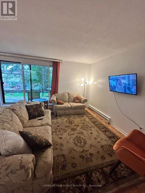 Toronto (Hillcrest Village) townhouse for rent - A living room with a couch, a chair, a rug, and a flat screen TV.