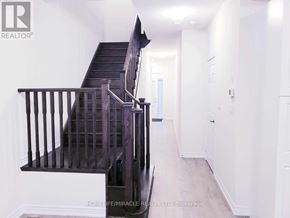 Caledon townhouse for rent - A staircase with a wooden handrail and a wall-mounted light fixture.