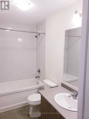 Caledon townhouse for rent - A white toilet is in a bathroom with a white tub and sink.