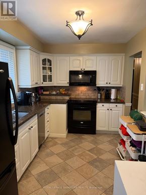 Oakville (Wo West) apartment for rent - A kitchen with black appliances and white cabinets.