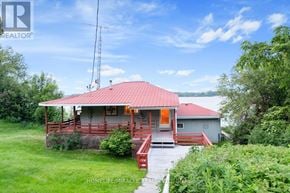 Prince Edward County (Picton Ward) apartment for rent - A house with a red roof and a deck is surrounded by greenery.