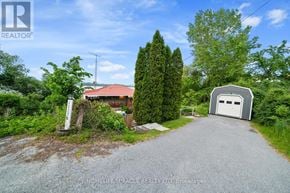 Prince Edward County (Picton Ward) apartment for rent - A gravel driveway leads to a garage with a house in the background.
