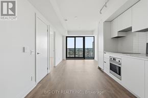 Toronto (Leaside) condo for rent - A spacious kitchen with white cabinets and a view of the city through the windows.