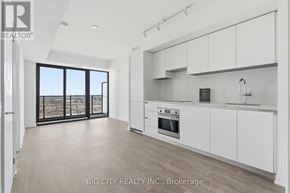 Toronto (Leaside) condo for rent - A spacious kitchen with white cabinets and a view of the city.