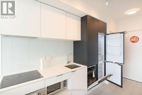 Toronto (Yonge-Eglinton) condo for rent - A modern kitchen with white and black cabinets and a refrigerator with the door open.