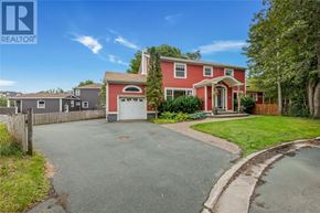 St. John's apartment for rent - A red house with a white garage door is surrounded by a green lawn and trees.