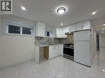 Vancouver apartment for rent - A white kitchen with a marble backsplash and a large island.