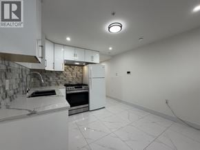 Vancouver apartment for rent - A kitchen with white appliances and a stone backsplash.