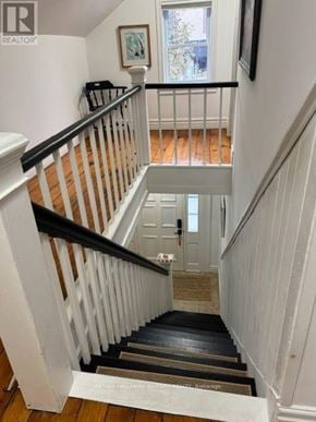 Selwyn apartment for rent - A staircase with a black railing and wooden steps leading to a door.