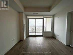 Pickering (Bay Ridges) condo for rent - A spacious room with a view of the city through a large window.
