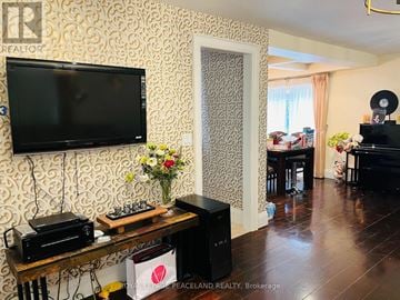 Newmarket (Summerhill Estates) apartment for rent - A living room with a television, a wooden table with a radio and flowers, and a doorway leading to another room.