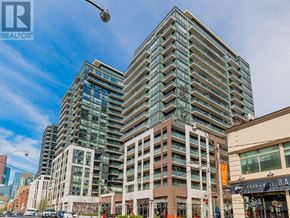 Toronto (Moss Park) condo for rent - A tall building with many windows is in the foreground of a city street.