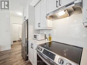 Richmond Hill (Oak Ridges) townhouse for rent - A kitchen with a black stove top oven and white cabinets.