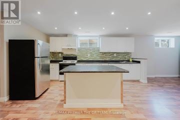 Vaughan (West Woodbridge) apartment for rent - A kitchen with a black fridge and a stone backsplash.