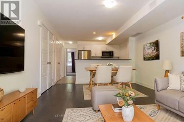 Kitchener townhouse for rent - A living room with a grey couch, a wooden coffee table, and a television on the wall.