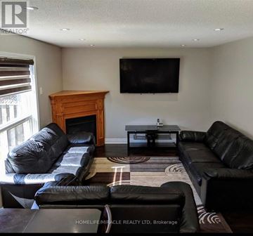 Brampton (Fletcher's Meadow) apartment for rent - A living room with a black leather couch and a wooden fireplace.