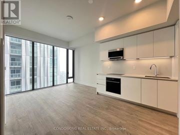 Toronto (Annex) condo for rent - A spacious kitchen with white cabinets and a wooden floor.