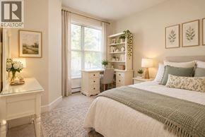 Vancouver apartment for rent - A bedroom with a large bed, a desk with a chair, and a window with a view of trees.