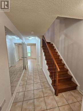 Toronto (Hillcrest Village) townhouse for rent - A hallway with a staircase and a mirror on the wall.