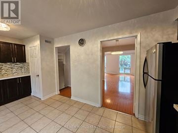 Toronto (Hillcrest Village) townhouse for rent - A kitchen with white cabinets and a black refrigerator.
