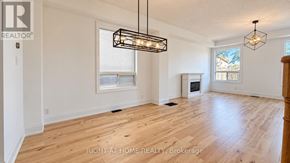 Oshawa (Windfields) apartment for rent - A spacious room with wooden flooring and a large window.