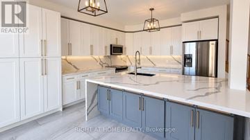 Oshawa (Windfields) apartment for rent - A kitchen with white cabinets and a marble countertop.