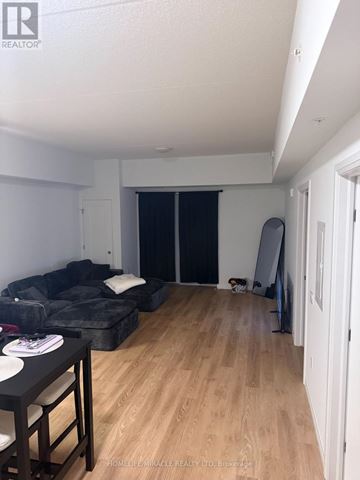 London East (East K) condo for rent - A living room with a black couch and a wooden floor.