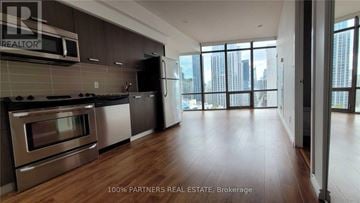Toronto (Bay Street Corridor) condo for rent - A modern kitchen with stainless steel appliances and wooden flooring.