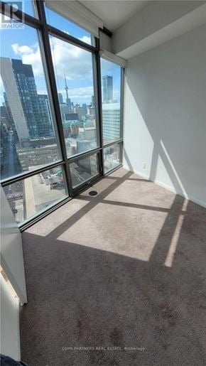 Toronto (Bay Street Corridor) condo for rent - A carpeted room with a view of the cityscape outside.