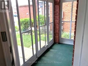 Newmarket (Gorham-College Manor) apartment for rent - A room with a green carpet and a view of a garden through the glass doors.