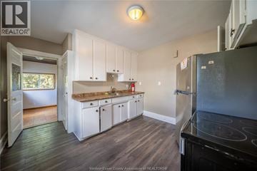 Windsor apartment for rent - A kitchen with white cabinets and a black stove top oven.
