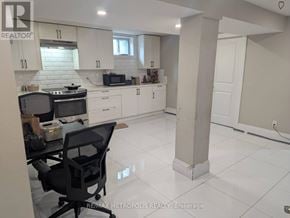 Toronto (Dorset Park) apartment for rent - A kitchen with white cabinets and a black chair.