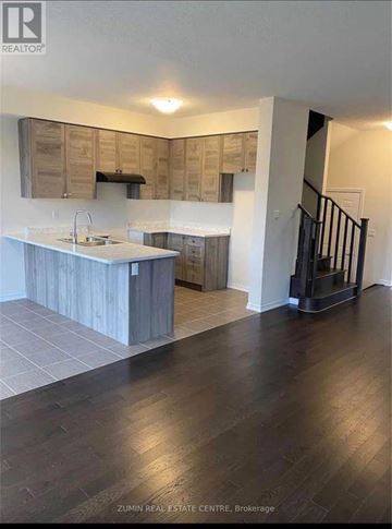 Niagara Falls (Brown) townhouse for rent - A modern kitchen with wooden cabinets and a black staircase.