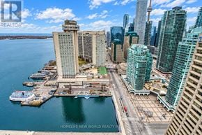 Toronto (Waterfront Communities) condo for rent - A cityscape with a body of water in the foreground and a clear blue sky above.