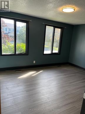 Clarington (Courtice) apartment for rent - A room with wooden flooring and two windows.