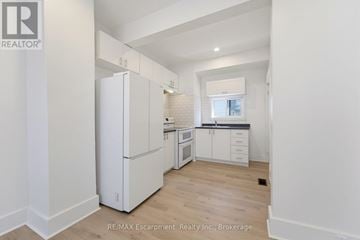 Brantford multi-family for rent - A white refrigerator in a kitchen with wooden floors and white walls.