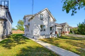 Brantford multi-family for rent - A white house with a red roof is surrounded by a grassy lawn.