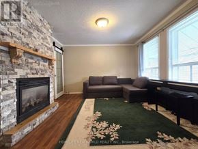 Hamilton (Eastmount) apartment for rent - A living room with a stone fireplace and a green rug.