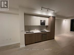 Toronto (Oakwood Village) condo for rent - A kitchen with wooden cabinets and a microwave built into the cabinetry.