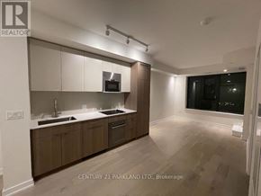 Toronto (Oakwood Village) condo for rent - A well-lit kitchen with wooden cabinets and a microwave above the stove.