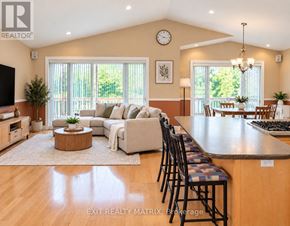 Casselman duplex for rent - A well-lit, spacious living room with a large window and a dining area in the background.